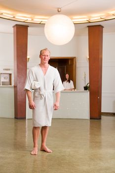 A man wearing a bathrobe in a day spa looking at camera