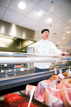 A butcher helping a customer at a fresh meat counter or deli