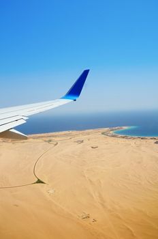 Airplane's wing under Egyptian desert and red sea coast with hotels