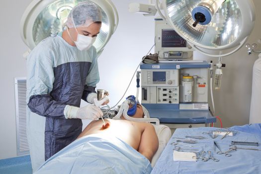 Male doctor performing operation on patient in operating room