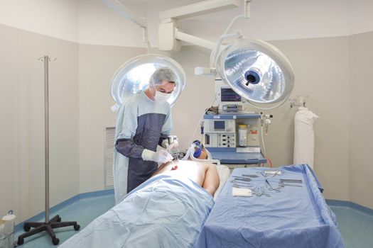 Young doctor performing operation on patient in operating room