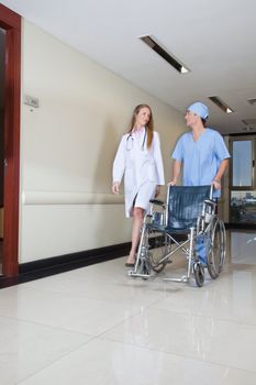 Doctor walking with male nurse pushing wheelchair