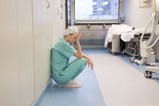 Tired doctor sitting alone in hallway