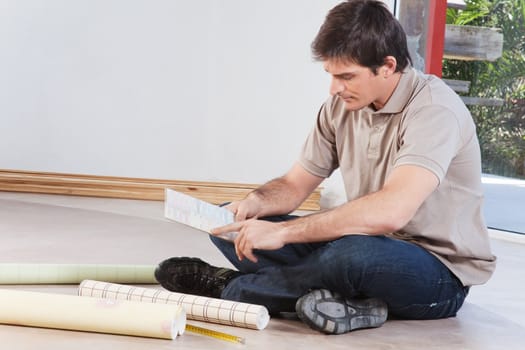 Young man sitting on floor looking at paint color swatch