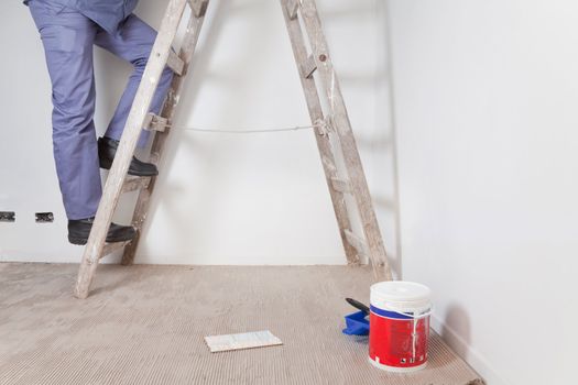 Low section of man's legs climbing wooden ladder