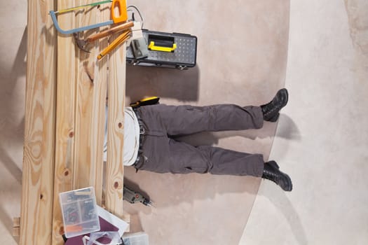 Man working under the wooden plank with tools