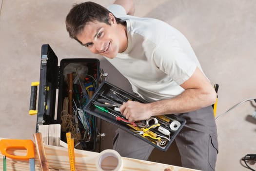 Portrait of smiling young man holding his tool box