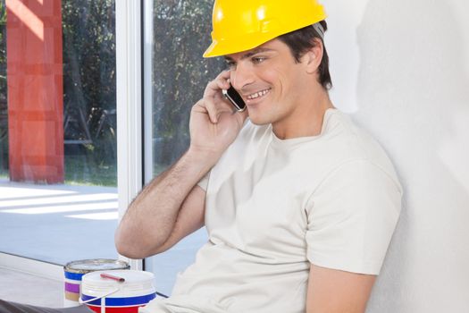 Smiling man with hard hat having conversation on mobile phone