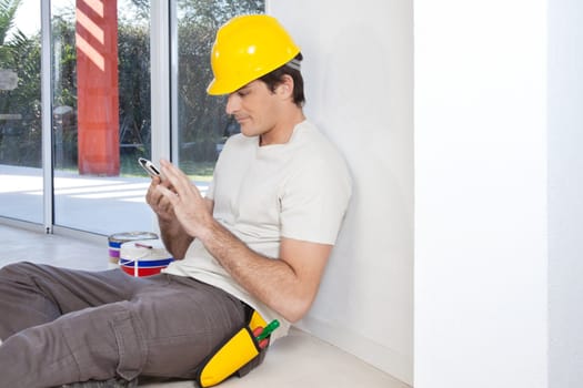 Construction worker looking in cellphone while sitting