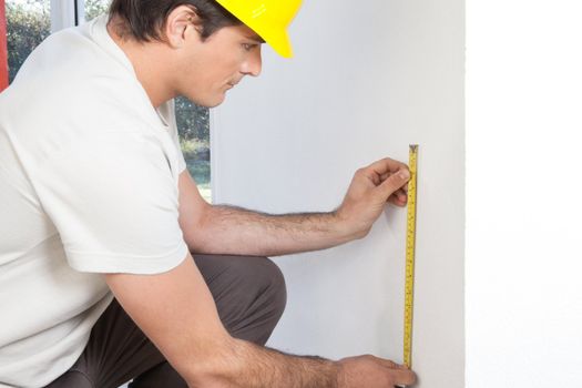 Young contractor measuring the wall for repairing