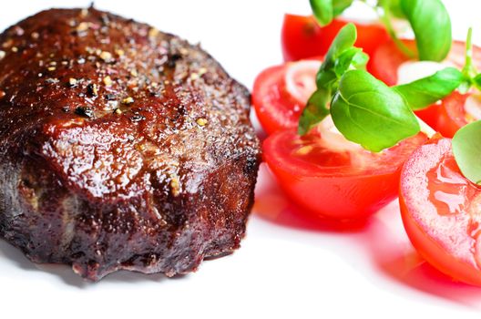 Steak with tomatoes and basil close up