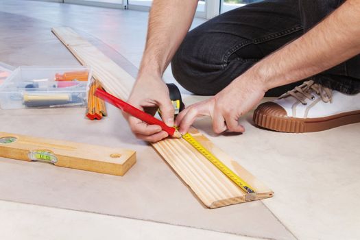 Man marking on plywood with measuring and pencil