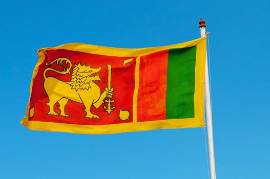 Sri Lanka flag on flagstaff. The lion represents the Sinhalese ethnicity and the bravery of the Sri Lankan nation. The orange stripe represents the Tamils, the green stripe represents Moors.