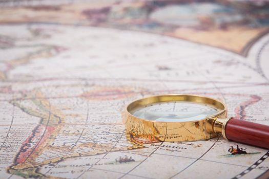 A beautiful antique map with an old magnifying glass with golden details.