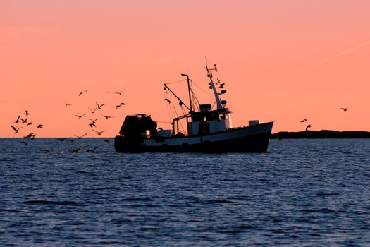 Norwegian fishingboat in silhouette sunrice.