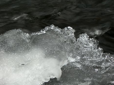 Flowing water in a brook is covered by clear ice
