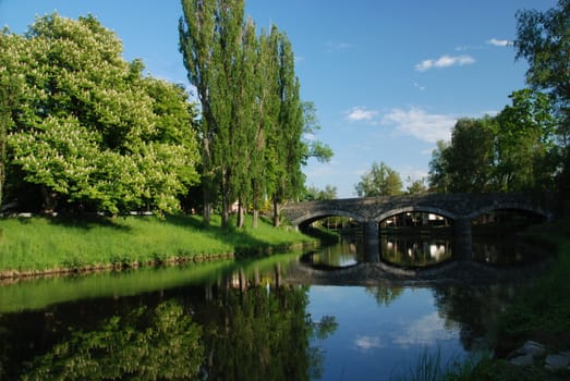 Park in the Czech town Breznice.Focus on river and old bridge