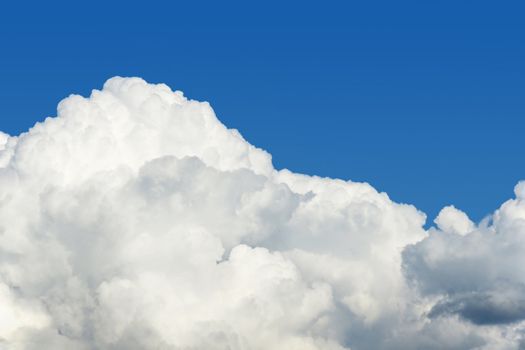 Beautiful white puffy cumulus clouds over a perfect blue sky, superb nature background with copy space.