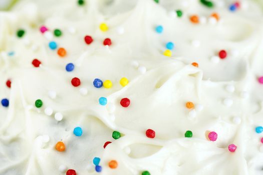 Great appetizing background of cream cheese cake frosting or icing with colorful sugar candy.