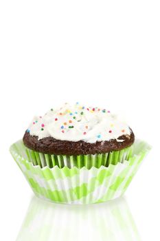 Delicious chocolate cupcake topped with  cream cheese frosting and colorful candy over reflective white background for copy space.