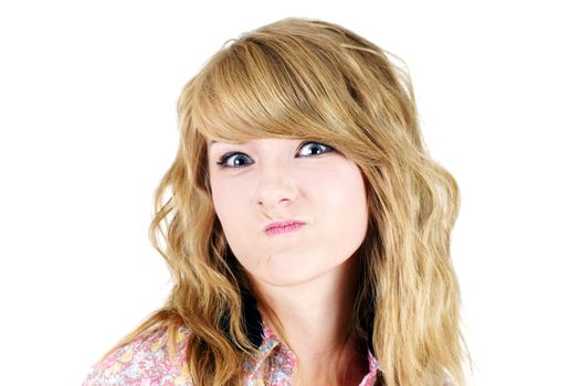 Cute young blond teenager girl making a funny unhappy or upset face, studio shot on white.