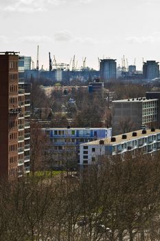 View over suburb Vlaardingen, the Netherlands, with appartment buildings and skyline port of Rotterdam with cranes in background