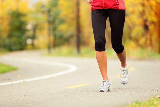 Runner legs and running shoes. Woman jogging in fall colors on forest path.