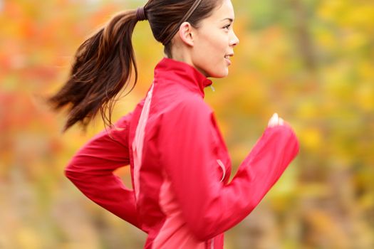 Running in Fall. Runner woman jogging in autumn forest. Beautiful young fit fitness sport model jogging with slight motion blur. Mixed race Caucasian / Asian girl.