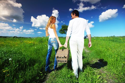 man and woman walk on picnic in green grass