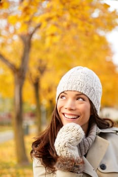 Fall woman thinking looking up in yellow autumn forest. Young happy smiling mixed race Caucasian and Chinese asian woman outdoors in city forest park.