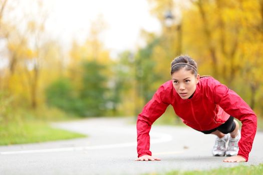 crossfit woman doing push-ups during outdoor cross training workout. Beautiful young and fit fitness sport model training outside in fall.