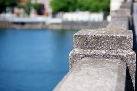 Concrete Bridge Railing with river and city shoreline visible in soft focus