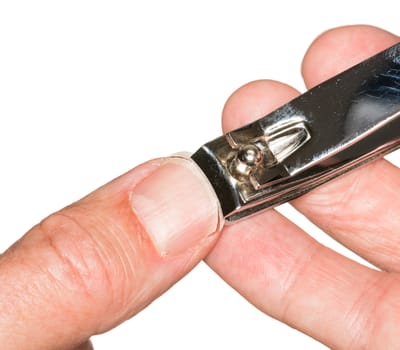 Macro photo of a set of nail clippers cutting thumbnail on senior caucasian thumb