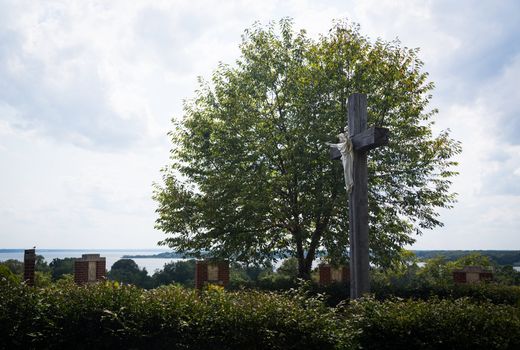 Statue of Christ being crucified on cross in stations of the cross overlooking estuary