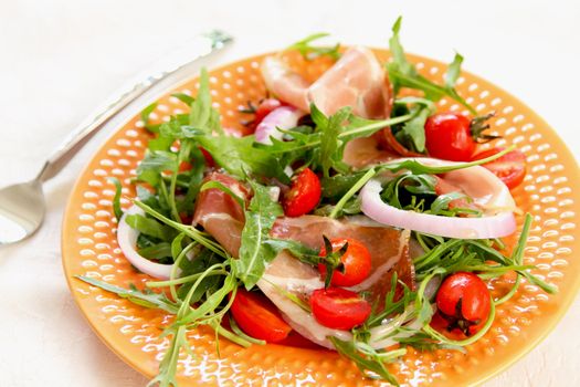 Prosciutto withcherry tomato,and rocket salad on orange dish