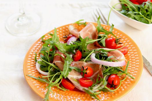 Prosciutto withcherry tomato,and rocket salad on orange dish