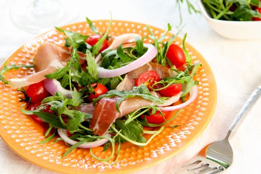 Prosciutto withcherry tomato,and rocket salad on orange dish