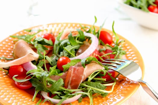 Prosciutto withcherry tomato,and rocket salad on orange dish