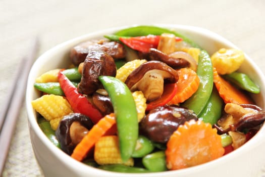 Stir fried vegetables with mushroom in white bowl by chopstick