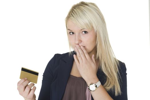 Beautiful blonde woman with a guilty look and her hand to her mouth holding up her credit card on which she has gone on a spending spree and overspent