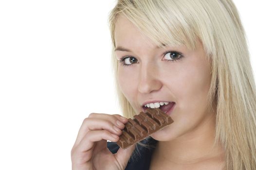 Attractive blonde woman eating a bar of chocolate with enjoyment isolated on white with copyspace
