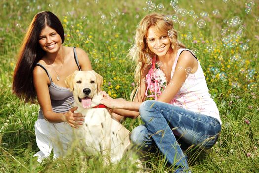 girlfriends and dog in green grass field