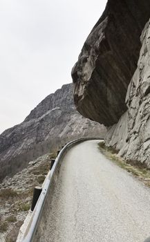 rock hanging over small road in the mountains of norway