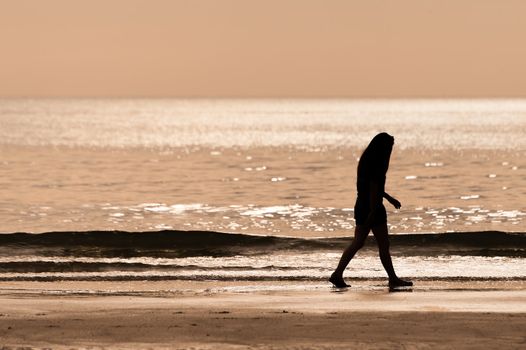 sillhouette woman walking on the beach