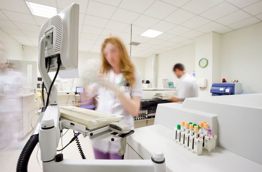 Blurred figures of busy people with medical uniforms in clinical laboratory