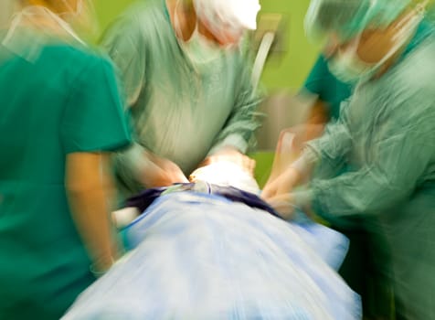 Blurred figures of surgeonts in medical uniforms performing surgery