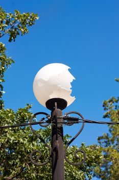 Broken white street lamp in city park