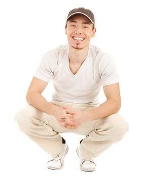 Casual smiling young man in a hat is sitting on white.