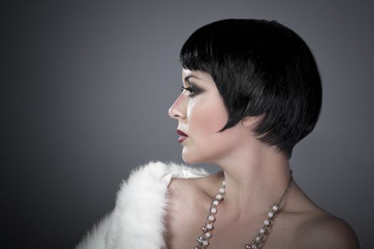 gourgeos female brunette flapper profile wearing pearls and fur, vintage look