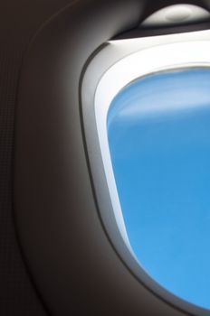 airplane window with bright blue skies visible - can easily be exchanded by your favourite view